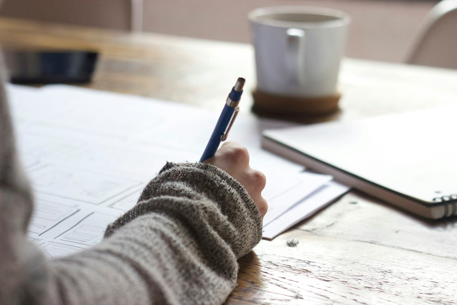 Notebook, pen and laptop on a desk in soft daylight